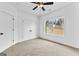 Bright bedroom featuring a ceiling fan, carpeted floors, and a window offering a view of the outdoors at 130 Windchime Way # 9, Tyrone, GA 30290