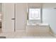 Bright bathroom showcasing a soaking tub beneath a decorative window and a doorway in the background at 3435 Vista Creek Dr, Dacula, GA 30019