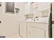 Functional laundry room with white washer and dryer, storage cabinets, ironing board, and chalkboard decor at 3435 Vista Creek Dr, Dacula, GA 30019