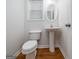 Well-lit half bath featuring a pedestal sink, wood flooring, and a window for natural light at 1870 Wildcat Trace Cir, Lawrenceville, GA 30043