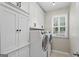 Well-lit laundry room with front load washer and dryer, white cabinets, and a window with shutter blinds at 240 Longmead Dr, Fayetteville, GA 30215