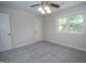 Well-lit bedroom featuring a ceiling fan, neutral paint, a large window, and plush gray carpeting at 101 Bluegill Trce, Peachtree City, GA 30269
