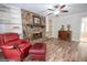 Inviting living room featuring wood floors, stone fireplace, built-in shelves, and a ceiling fan at 101 Bluegill Trce, Peachtree City, GA 30269