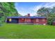 Backyard view of the home featuring a brick exterior, a large lawn and mature trees at 1091 Pine St, Conyers, GA 30012
