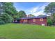 Backyard view of the home featuring a brick exterior, a large lawn and mature trees at 1091 Pine St, Conyers, GA 30012