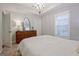 Bright bedroom features tray ceiling, a large window, and a classic wooden dresser with a mirror at 405 Bandon Way, Peachtree City, GA 30269