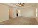 A large bedroom leading to bathroom and closets with carpet flooring and a ceiling fan at 321 Champions Dr, Fairburn, GA 30213
