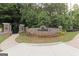 Stone entrance to Durham Lakes Golf and Country Club, featuring manicured flower beds and mature trees at 321 Champions Dr, Fairburn, GA 30213