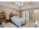 Comfortable bedroom featuring a decorative tray ceiling, ceiling fan, and a cozy bed at 556 Walton Dr, Social Circle, GA 30025