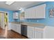Kitchen featuring white cabinetry, stainless steel dishwasher, and wood-look flooring at 556 Walton Dr, Social Circle, GA 30025