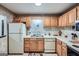Kitchen with wood cabinetry, white appliances, and wallpaper border at 578 Mcgill Ne Pl # 578, Atlanta, GA 30312