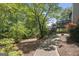 Lush backyard with mature trees, walkway, and wooden deck at 9206 Denmeade Trce, Douglasville, GA 30135