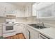 Bright kitchen featuring white cabinets, countertops, and appliances, with a stainless steel double sink at 4954 Browns Mill Rd, Lithonia, GA 30038