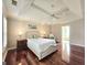 Bedroom featuring hardwood floors, a tray ceiling with a ceiling fan, and a comfortable bed with lamps at 110 Vicarage Ct, Johns Creek, GA 30005