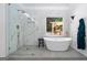 Modern bathroom featuring a glass shower, soaking tub, and backyard view at 3707 Lance Bluff Ln, Duluth, GA 30097