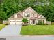 Spacious two-story home with lush green lawn, tree line, and a three-car garage and driveway at 3707 Lance Bluff Ln, Duluth, GA 30097