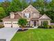 Charming two-story brick home featuring a manicured lawn, three-car garage, and professionally landscaped yard at 3707 Lance Bluff Ln, Duluth, GA 30097
