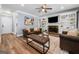Living room with hardwood floors, tufted ottoman, and built-in shelves with a fireplace and wall-mounted television at 3707 Lance Bluff Ln, Duluth, GA 30097