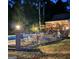 Backyard pool illuminated by patio lights, surrounded by a security fence and chairs at 604 Clearwater Ct, Mcdonough, GA 30252
