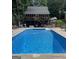 Clear blue in-ground pool with an adjacent house that has a deck with chairs and a table at 604 Clearwater Ct, Mcdonough, GA 30252