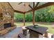 Covered outdoor patio boasting a stone fireplace, wooden beams, and a view of the private backyard at 71 Pacific Ave, Sharpsburg, GA 30277