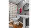 Cozy bathroom featuring a pedestal sink, decorative mirror, and colorful bird-themed shower curtain at 145 Oxford Ln, Fayetteville, GA 30215