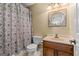 Bathroom with a patterned shower curtain, wooden vanity, and round mirror at 145 Oxford Ln, Fayetteville, GA 30215