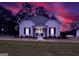 Charming home illuminated with a warm glow, with a green metal roof and lush lawn at twilight at 111 S Old 27, Roopville, GA 30170