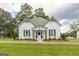 Charming white cottage with green metal roof, decorative shutters, and lush landscaped front yard at 111 S Old 27, Roopville, GA 30170