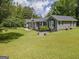 Serene home exterior featuring a manicured lawn, mature trees, and cozy front porch at 105 Greenfield Cir, Fayetteville, GA 30215