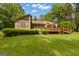 Rear exterior of the home with a large lawn, mature trees, a wooden deck and sunroom at 105 Gleneagles Pt, Peachtree City, GA 30269