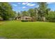 Rear exterior of the home with a large lawn, mature trees, a wooden deck and sunroom at 105 Gleneagles Pt, Peachtree City, GA 30269