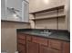 Cozy wet bar features wood cabinets, stainless steel sink, black countertop, and shelving for storage and drink preparation at 105 Gleneagles Pt, Peachtree City, GA 30269