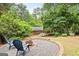 Cozy backyard fire pit area with seating, lush landscaping, and mature trees at 3571 Lake Se Dr, Smyrna, GA 30082
