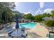 Community pool with lounge chairs and table seating with a sun umbrella surrounded by trees at 701 Ridgelake Dr, Peachtree City, GA 30269