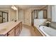 Well-lit bathroom featuring double vanity, soaking tub, glass-enclosed shower, and tile flooring at 1370 Sunnys Halo Dr, Suwanee, GA 30024