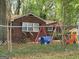 View of the backyard with a swing set and play area, surrounded by trees at 957 Astor Ave, Forest Park, GA 30297