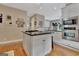 Kitchen island with white cabinets and black countertop, surrounded by stainless steel appliances and hardwood floors at 1214 Weatherstone Way, Peachtree City, GA 30269