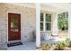 Inviting front porch featuring a stylish red door, brick facade, and comfortable seating area at 608 Belshire Dr, Acworth, GA 30102