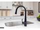 Close-up of a kitchen sink with a sleek black faucet, white cabinets, and a tiled backsplash at 608 Belshire Dr, Acworth, GA 30102