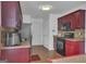 Galley kitchen with warm red cabinets, stainless steel appliances, and hardwood floors at 11367 Vinea Ln, Hampton, GA 30228