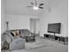 Bright, airy living room with gray sofa, TV, ceiling fan, and neutral-toned decor at 11367 Vinea Ln, Hampton, GA 30228