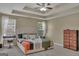 Spacious main bedroom featuring a tray ceiling, ceiling fan, carpet, and two windows for natural light at 11367 Vinea Ln, Hampton, GA 30228