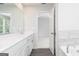 Bathroom with double sink vanity and mirror, tile accents, and doorway leading to bedroom at 407 Newland Way, Acworth, GA 30102