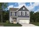 Two-story home with gray siding, brick accents, a two-car garage, and a well-manicured lawn under a partly cloudy sky at 407 Newland Way, Acworth, GA 30102