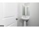 Modern powder room featuring a pedestal sink, a framed mirror, and a neutral color scheme at 407 Newland Way, Acworth, GA 30102