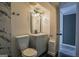 Bathroom featuring gray vanity, lighted mirror, neutral wall color, toilet, and black honeycomb floor tiles at 1772 Martin Se Pl, Smyrna, GA 30080