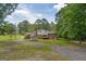 A backyard with green grass, trees, a utility shed, and a brick house at 6023 Highway 20 S, Covington, GA 30016