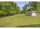 Expansive backyard featuring a fire pit, manicured lawn, and storage building surrounded by mature trees at 6023 Highway 20 S, Covington, GA 30016