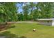 Well-maintained backyard with a fire pit, storage building, and manicured lawn bordered by mature trees at 6023 Highway 20 S, Covington, GA 30016
